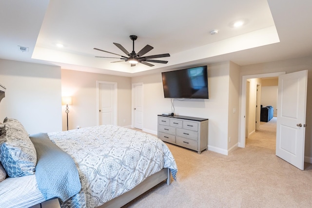 carpeted bedroom with a raised ceiling and ceiling fan