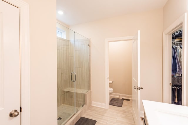 bathroom with a shower with door, vanity, and toilet