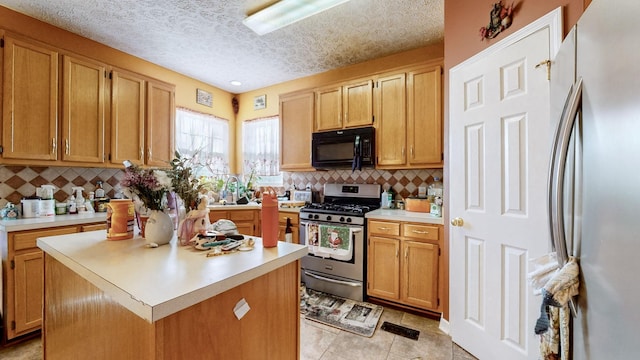 kitchen featuring decorative backsplash, stainless steel appliances, a textured ceiling, and a kitchen island