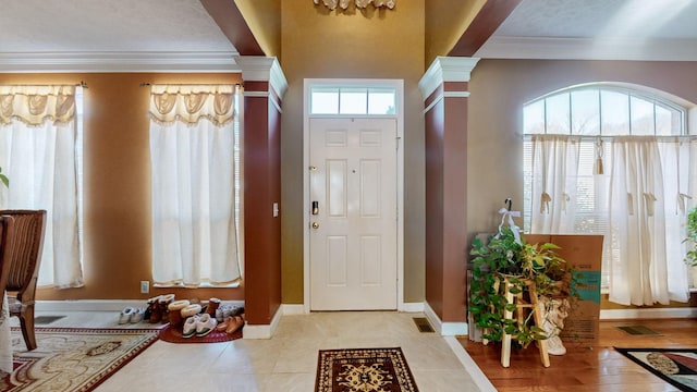 tiled entrance foyer with ornamental molding and decorative columns