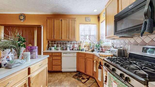 kitchen with stainless steel range with gas cooktop, dishwasher, sink, backsplash, and a textured ceiling