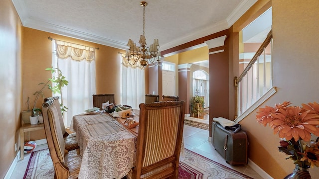 dining area with tile patterned flooring, ornamental molding, and a notable chandelier