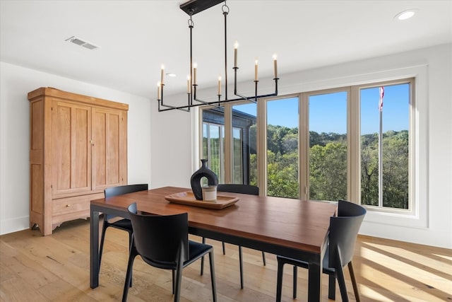 dining area featuring plenty of natural light, light hardwood / wood-style floors, and an inviting chandelier