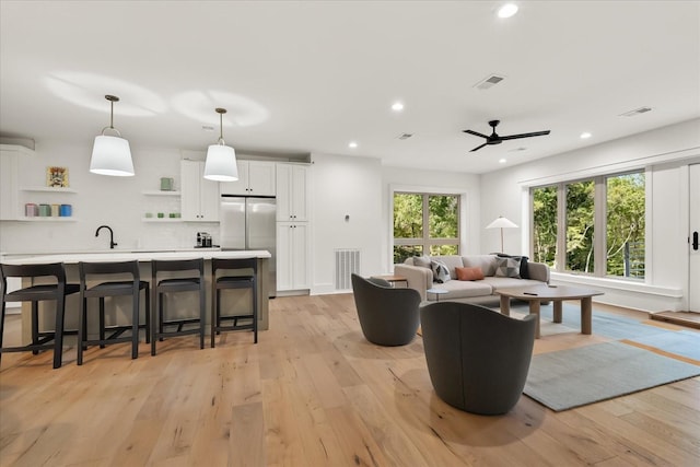 living room featuring light hardwood / wood-style floors, ceiling fan, and sink