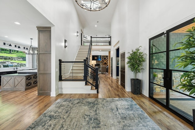 entryway with a towering ceiling and light wood-type flooring