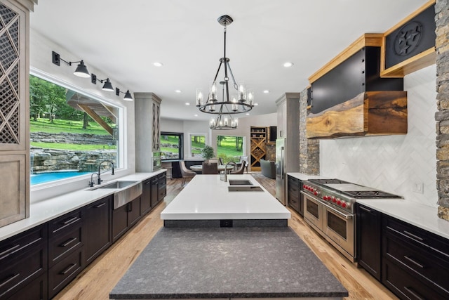 kitchen with backsplash, sink, a spacious island, and range with two ovens