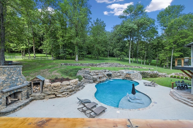 view of swimming pool featuring pool water feature, a yard, a patio, and an outdoor stone fireplace