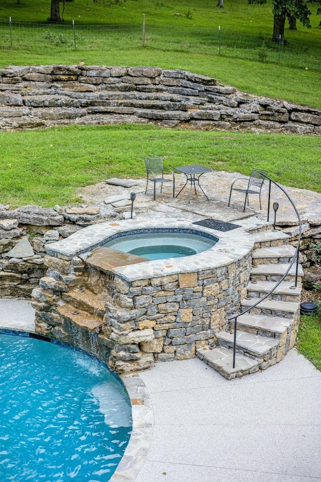 view of swimming pool featuring a lawn, an in ground hot tub, and pool water feature