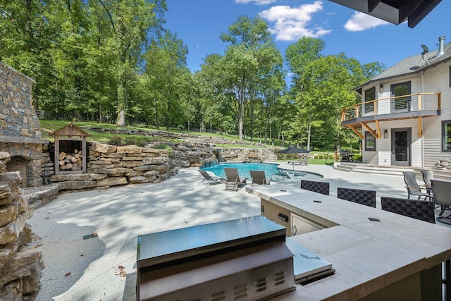 view of patio featuring an outdoor stone fireplace and a balcony