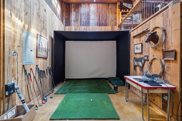 interior space with wood walls, golf simulator, electric panel, and concrete floors