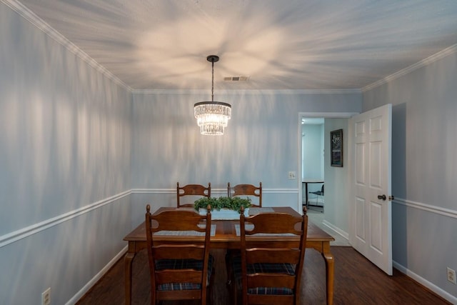 dining area featuring ornamental molding, dark wood-type flooring, and an inviting chandelier