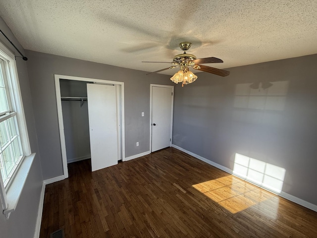 unfurnished bedroom with ceiling fan, dark hardwood / wood-style floors, a textured ceiling, and a closet