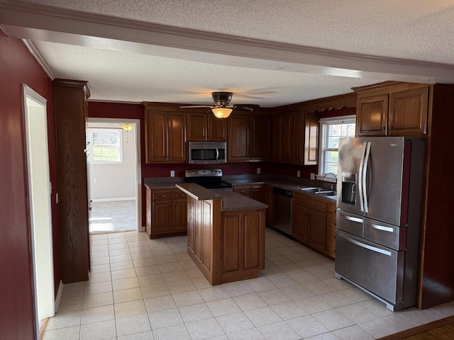 kitchen featuring sink, ceiling fan, a textured ceiling, a kitchen island, and stainless steel appliances