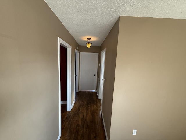 corridor with a textured ceiling and dark wood-type flooring