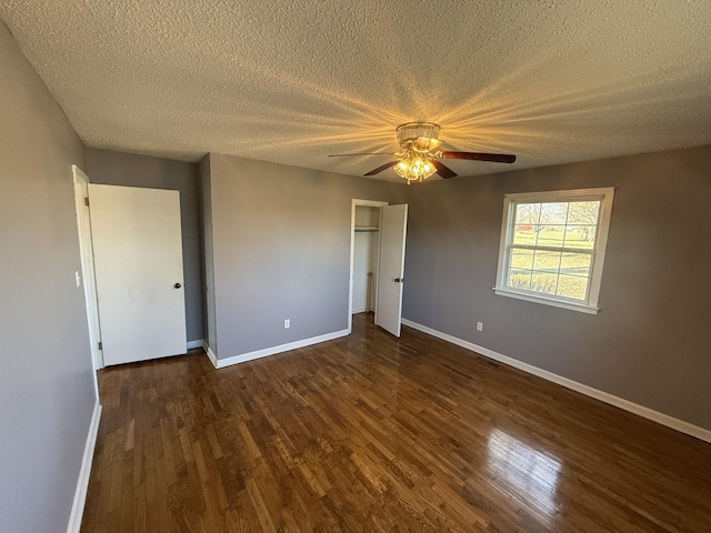 unfurnished bedroom with ceiling fan, dark hardwood / wood-style flooring, and a textured ceiling