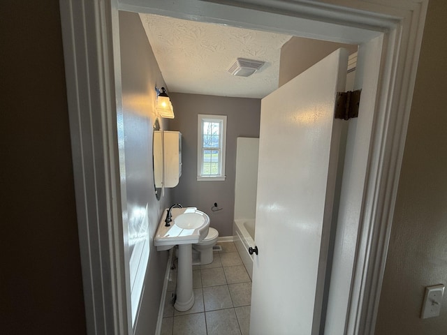 bathroom with a washtub, sink, tile patterned flooring, a textured ceiling, and toilet