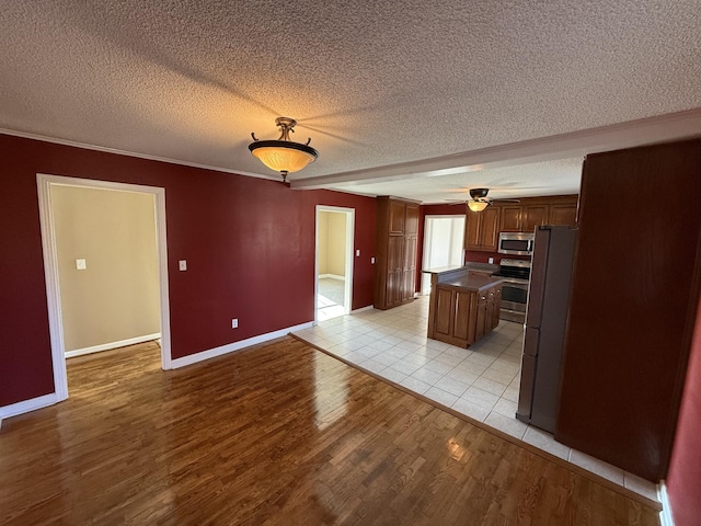 kitchen featuring appliances with stainless steel finishes, a textured ceiling, ceiling fan, light hardwood / wood-style flooring, and a center island