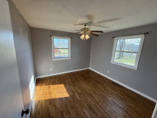 empty room with a textured ceiling, dark hardwood / wood-style flooring, and ceiling fan