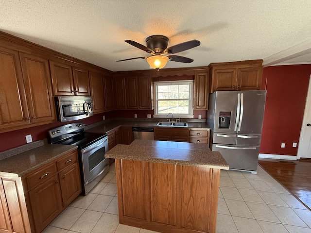 kitchen with sink, stainless steel appliances, a kitchen island, a textured ceiling, and light tile patterned flooring