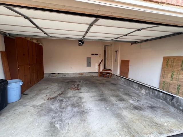 garage featuring electric panel and a garage door opener