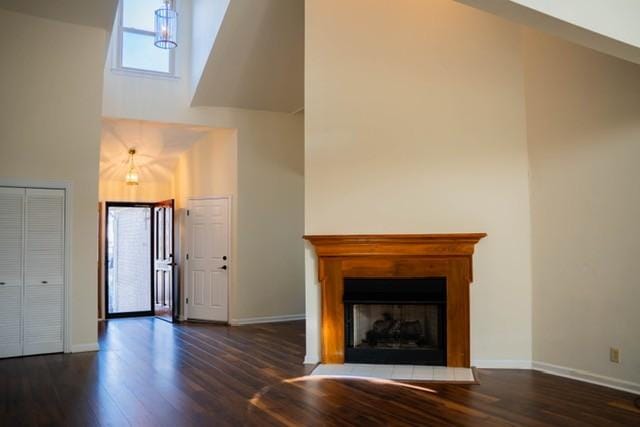 unfurnished living room featuring dark hardwood / wood-style flooring and a towering ceiling