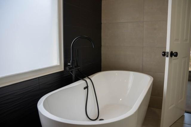 bathroom with tile walls and a tub