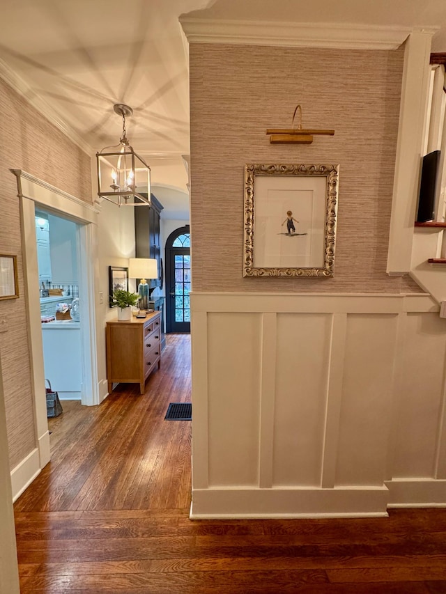 hallway featuring dark hardwood / wood-style flooring, ornamental molding, and a notable chandelier