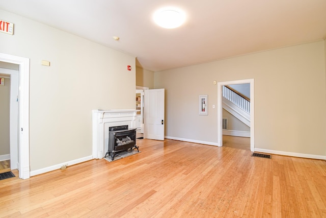 unfurnished living room with light hardwood / wood-style floors and a wood stove