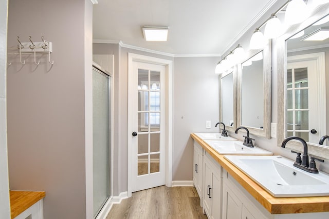 bathroom featuring hardwood / wood-style floors, vanity, a shower with shower door, and ornamental molding