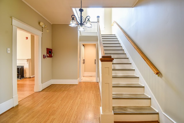 stairway with hardwood / wood-style flooring, an inviting chandelier, and ornamental molding