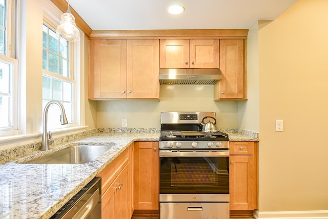 kitchen featuring hanging light fixtures, light stone countertops, sink, and appliances with stainless steel finishes