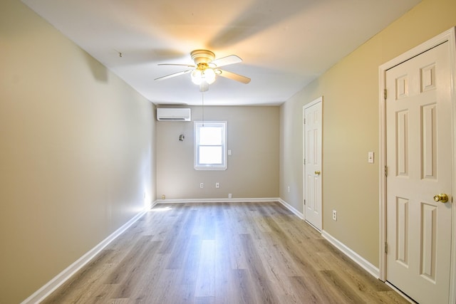 empty room with light hardwood / wood-style floors, a wall unit AC, and ceiling fan