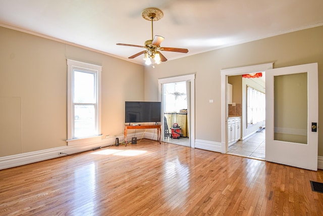 unfurnished living room featuring crown molding, ceiling fan, plenty of natural light, and light hardwood / wood-style floors