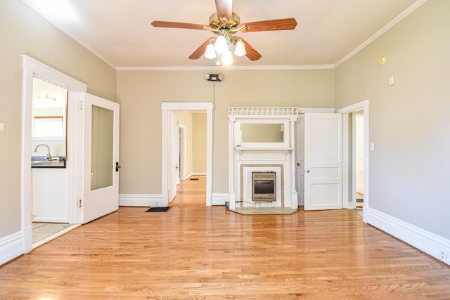 unfurnished living room featuring ceiling fan, ornamental molding, sink, and light hardwood / wood-style flooring