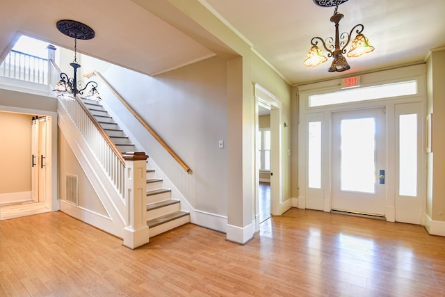 entryway with a chandelier, light wood-type flooring, and ornamental molding