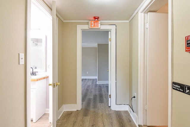 corridor featuring sink, light hardwood / wood-style floors, and ornamental molding