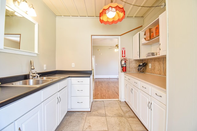 kitchen featuring ceiling fan, decorative backsplash, white cabinetry, and sink