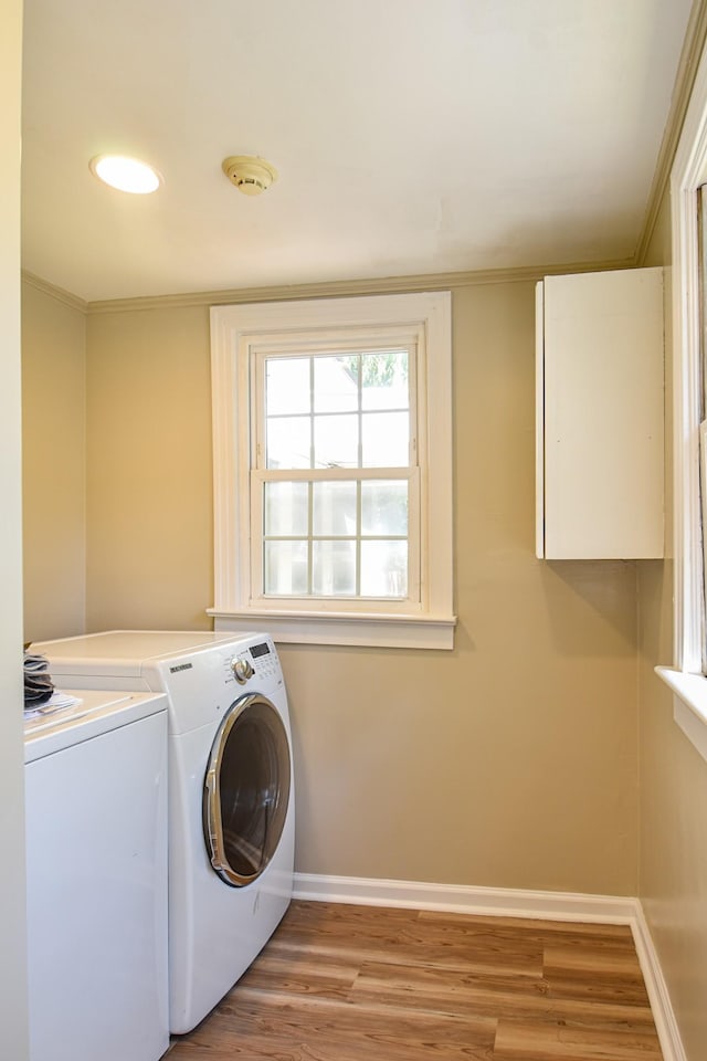 clothes washing area featuring washer and clothes dryer, light wood-type flooring, and ornamental molding