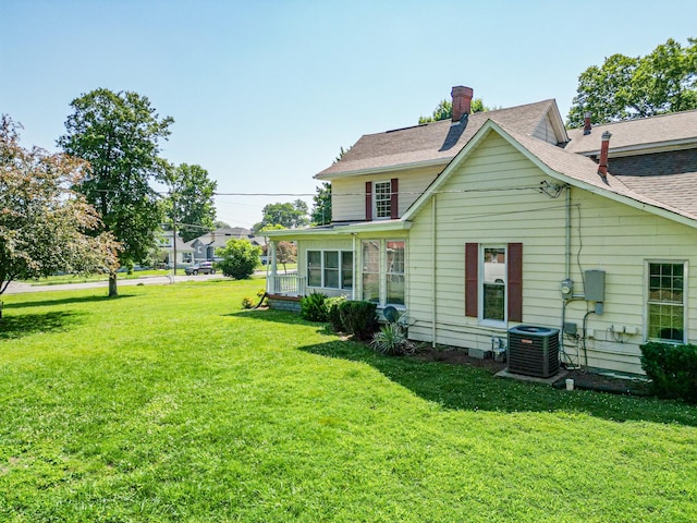 rear view of property with cooling unit and a yard