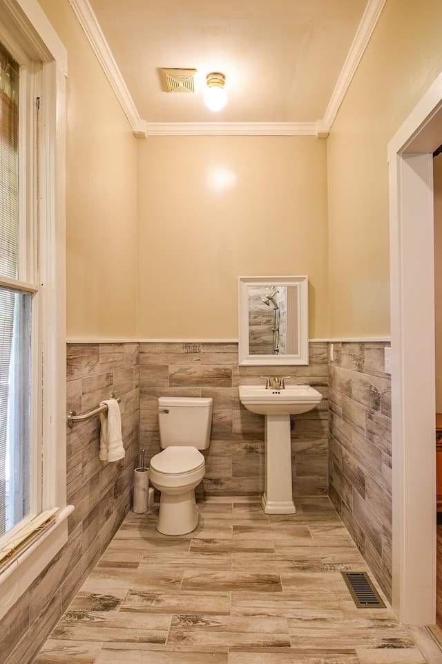 bathroom with crown molding, sink, tile walls, and toilet