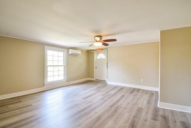 spare room featuring light hardwood / wood-style flooring, an AC wall unit, ceiling fan, and ornamental molding