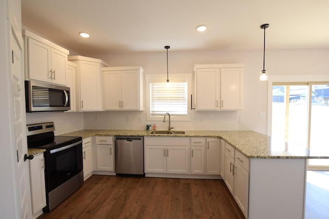 kitchen with kitchen peninsula, sink, pendant lighting, and appliances with stainless steel finishes