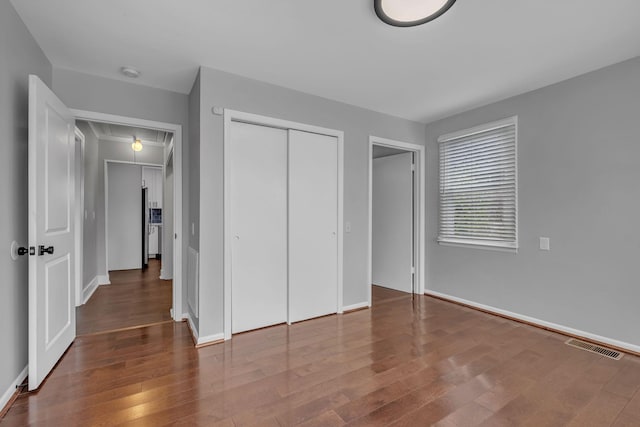 unfurnished bedroom with a closet and dark wood-type flooring