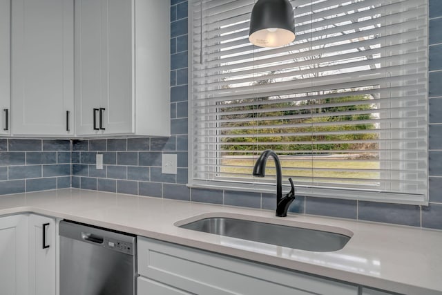 kitchen with stainless steel dishwasher, plenty of natural light, white cabinets, and sink