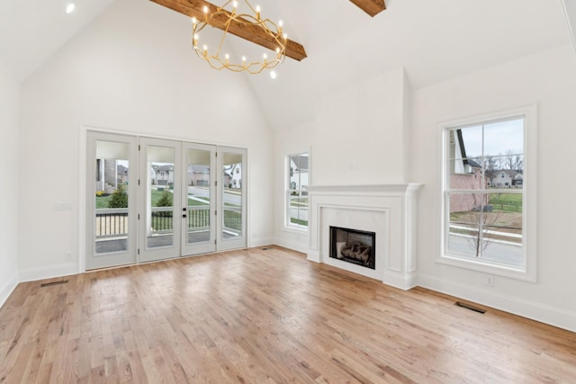 unfurnished living room featuring beam ceiling, light wood-type flooring, high vaulted ceiling, and a notable chandelier