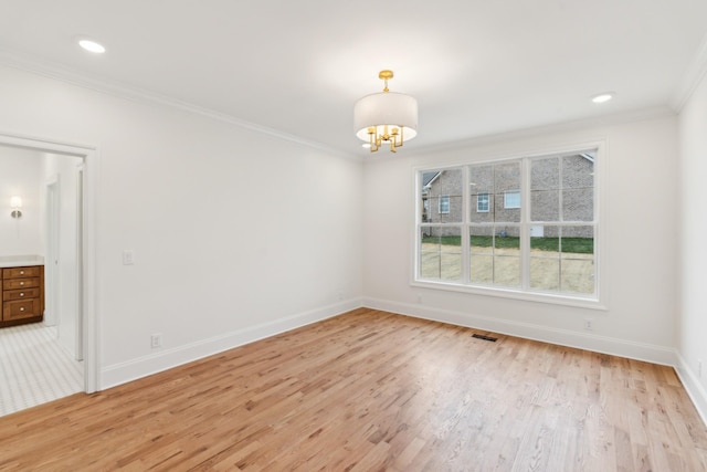 spare room featuring light hardwood / wood-style floors, ornamental molding, and an inviting chandelier