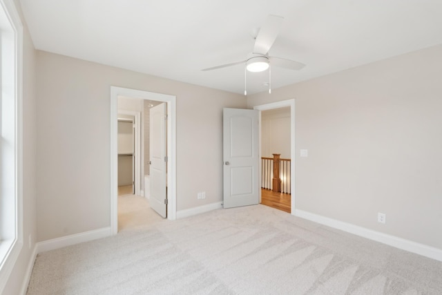 unfurnished bedroom with a walk in closet, ceiling fan, a closet, and light colored carpet