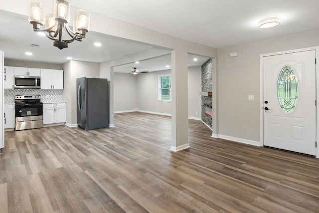 interior space with ceiling fan with notable chandelier and light hardwood / wood-style flooring