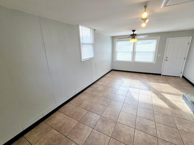 tiled empty room featuring ceiling fan