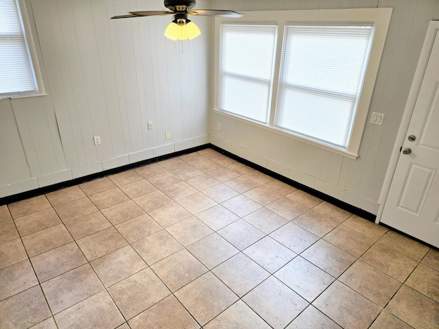 tiled spare room with ceiling fan and wood walls